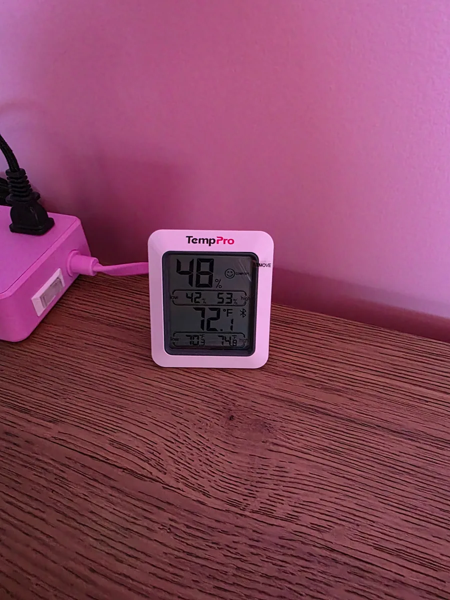 Digital hygrometer on a wooden desk reading 48% relative humidity and 72.1°F